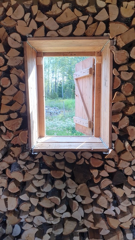 A window framed by a stacked woodpile